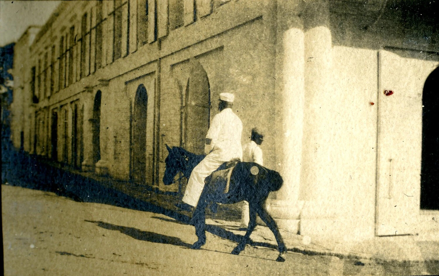 Sailor Riding a Mule Past Colonnaded Buildings, Foreign Port, USS Columbia Album, c. 1898-1910s
