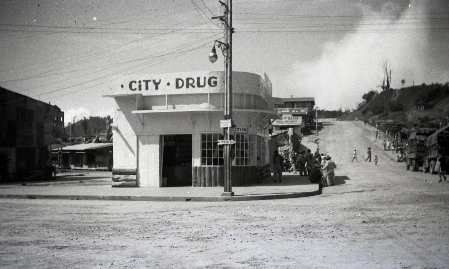 Street Corner View of 'City Drug' Store at Road Junction, Luzon, Philippines, WWII Era