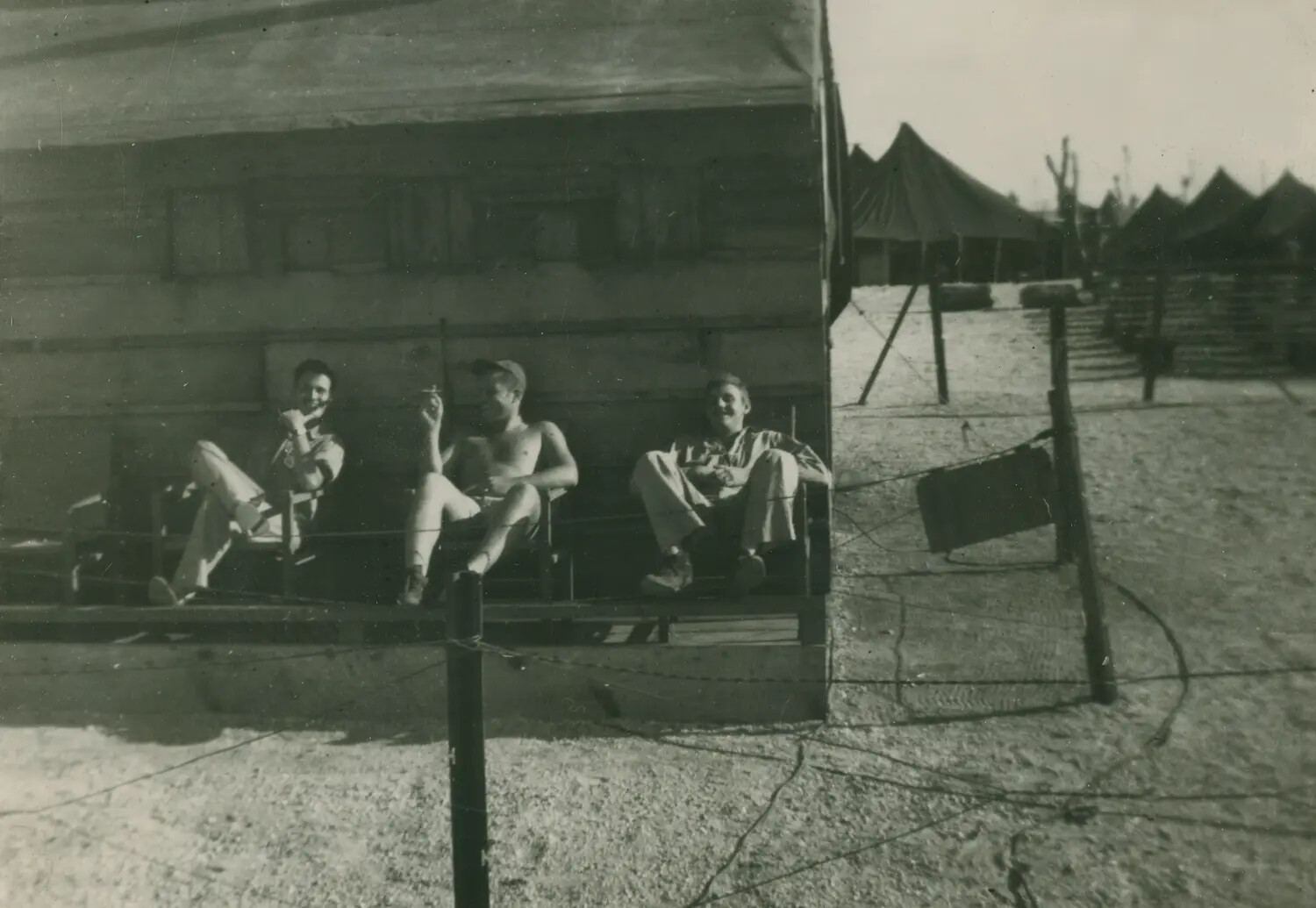 Servicemen Relaxing on Barracks Porch with Tent Camp in Background