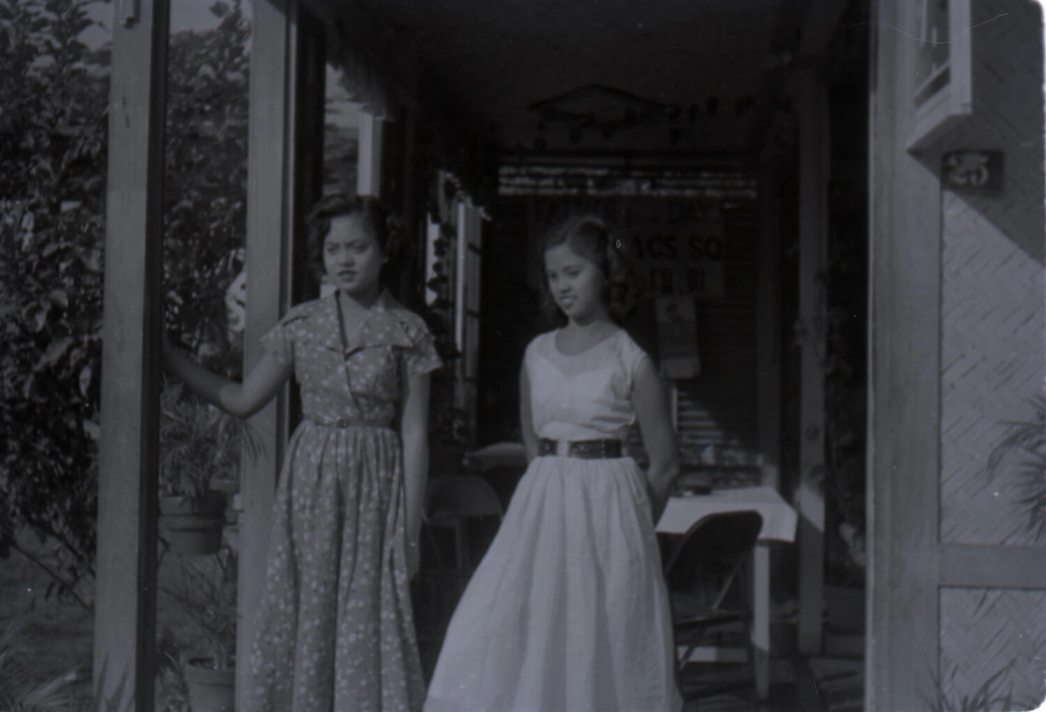 Two Young Women on a Porch, Philippines, with Military Unit Signage in Background