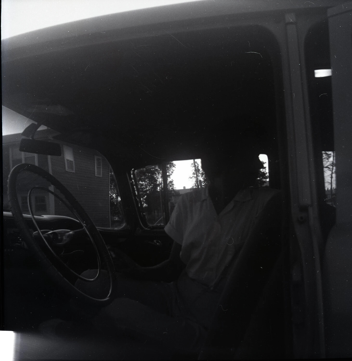 Underexposed Interior View of a Parked Car at Dusk with House in Background