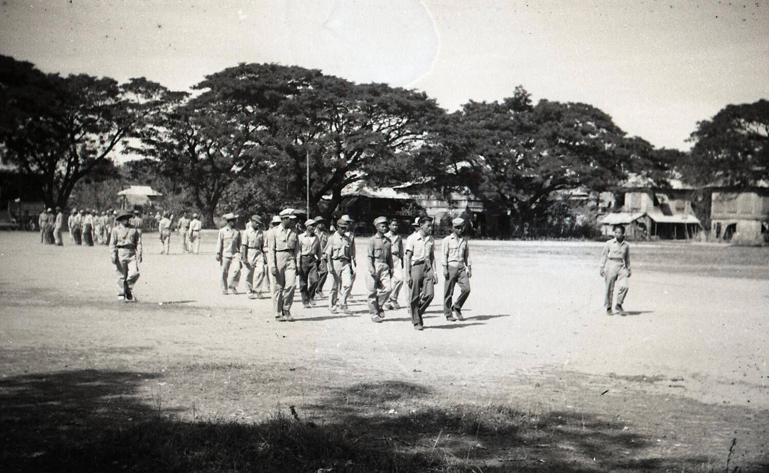 Filipino Men Marching in Formation Across a Town Plaza, Luzon, Philippines - WWII Era
