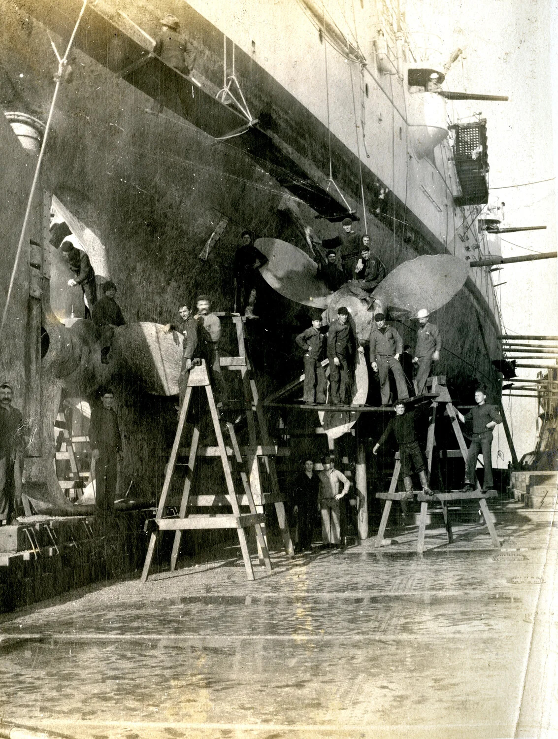 USS Columbia in Dry Dock: Stern View with Crew on Scaffolding Around the Propellers