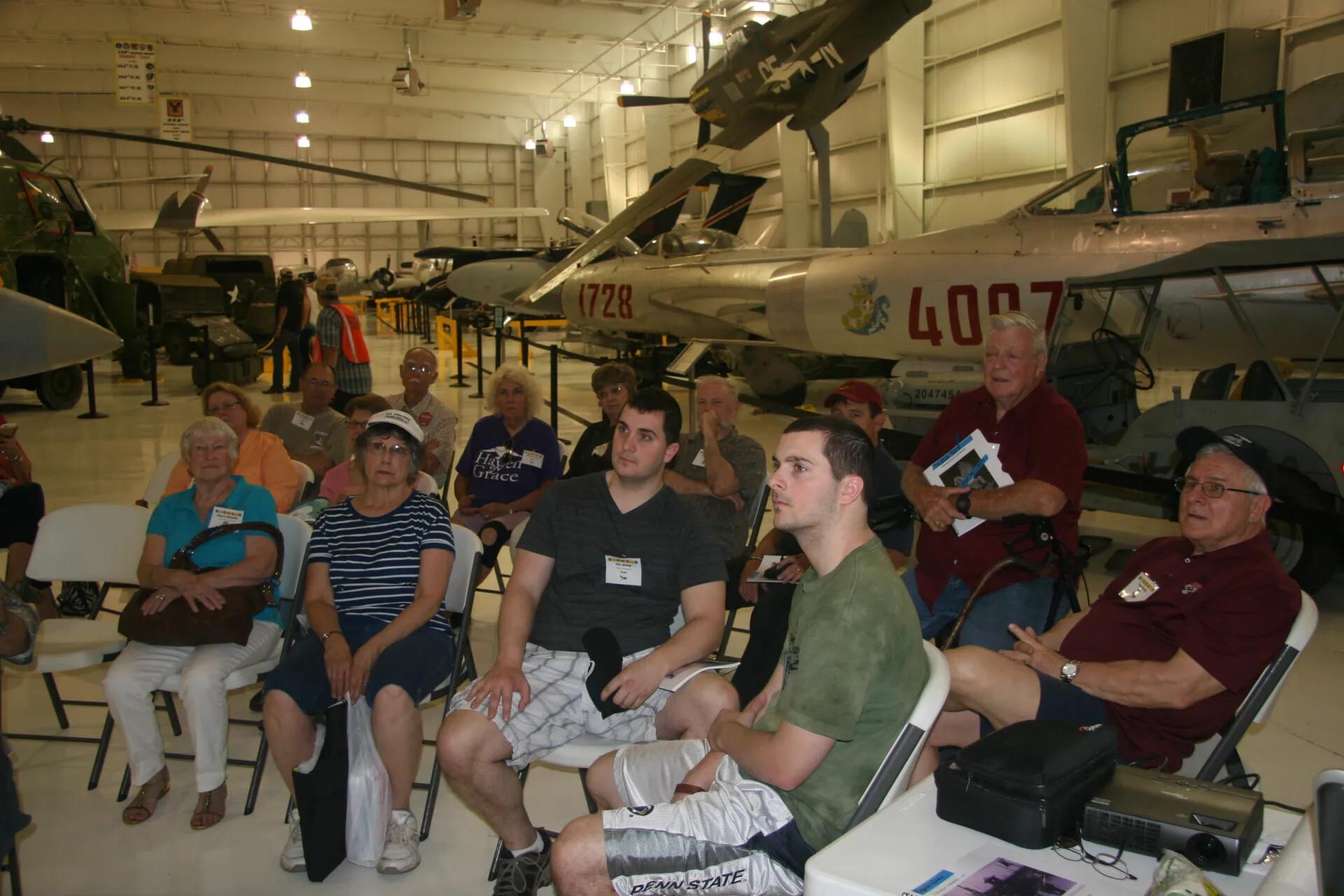 Reunion Audience Seated Among Cold War and Vietnam-Era Aircraft, Aviation Museum Hangar