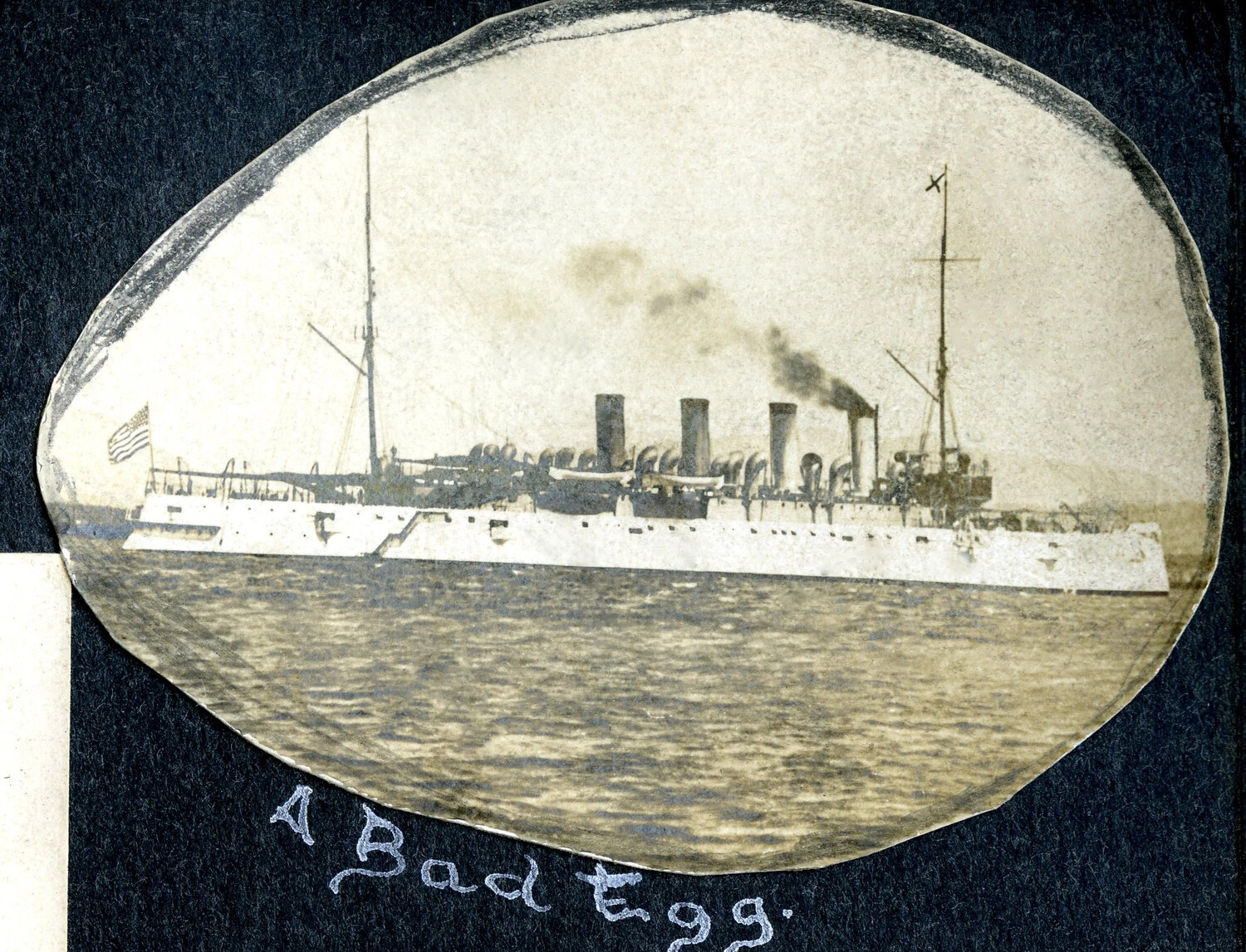 Oval Album Photograph of a Four-Stack U.S. Navy Protected Cruiser, Captioned "A Bad Egg," USS Columbia Album