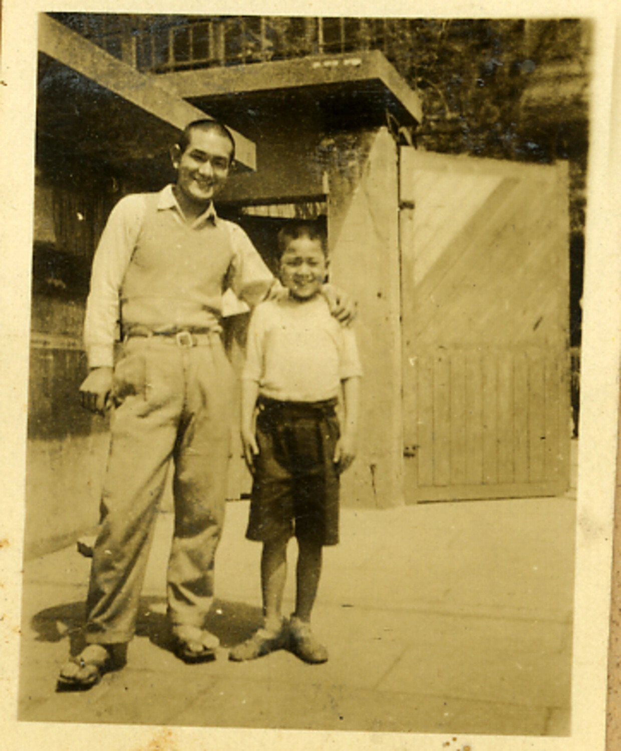 Informal Family Portrait of a Young Man and Boy Before a Wooden Gate, Japan, Mid-20th Century