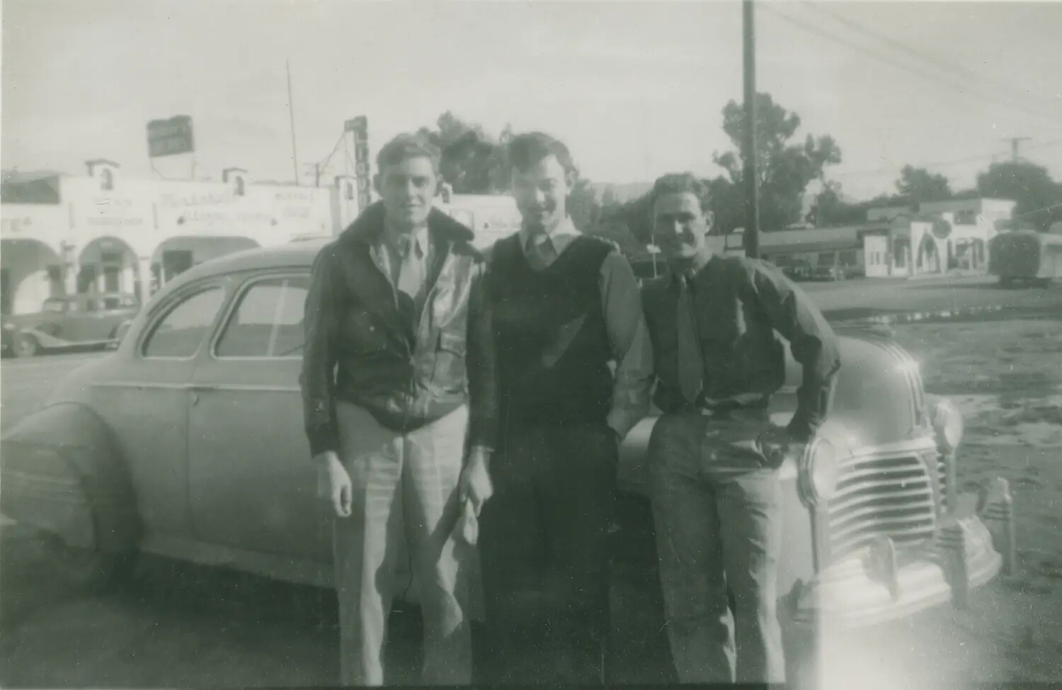 Three Young Men with Automobile on Small-Town Main Street, Edward P. McAleer Album