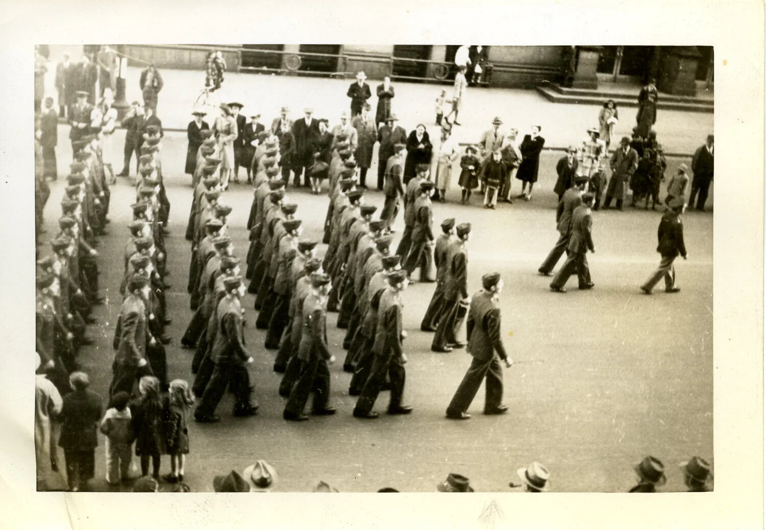 Elevated View of Marching Formation and Civilian Crowd in Urban Plaza, WWII Era