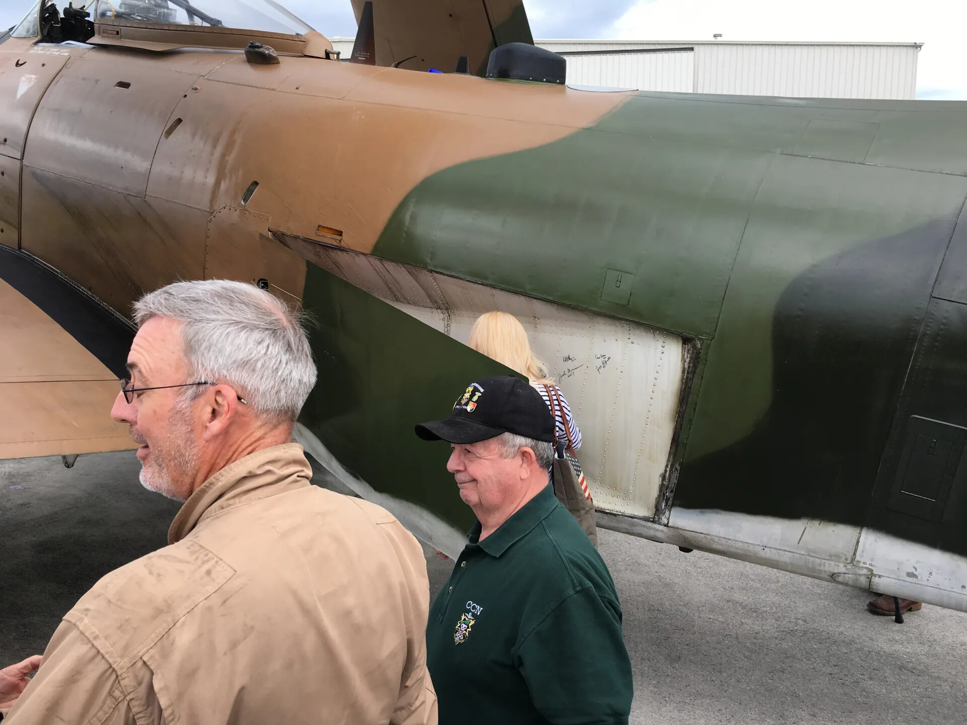 Veterans Inspect Signed Panel on Camouflaged Aircraft, 'Mel Swanson Day' Reunion