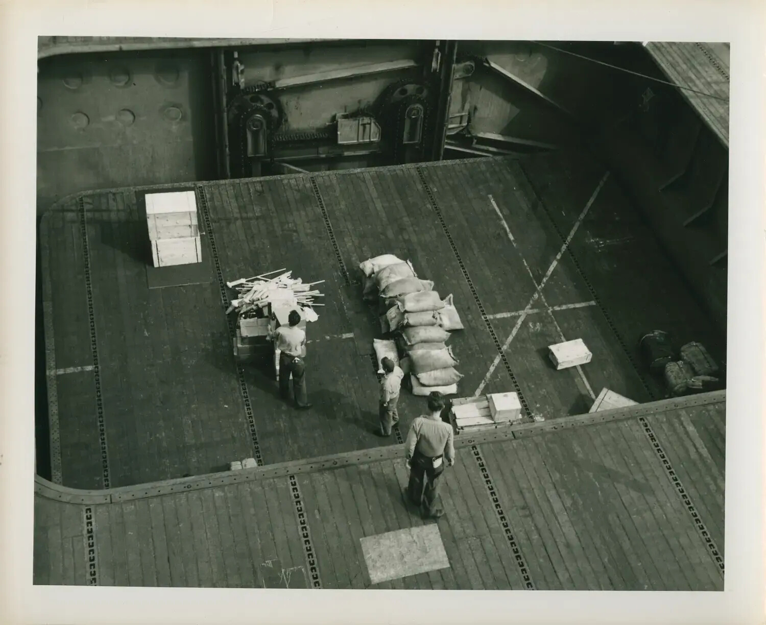 Sailors Handling Cargo Near Elevator Well Aboard USS Petrof Bay (CVE-80)