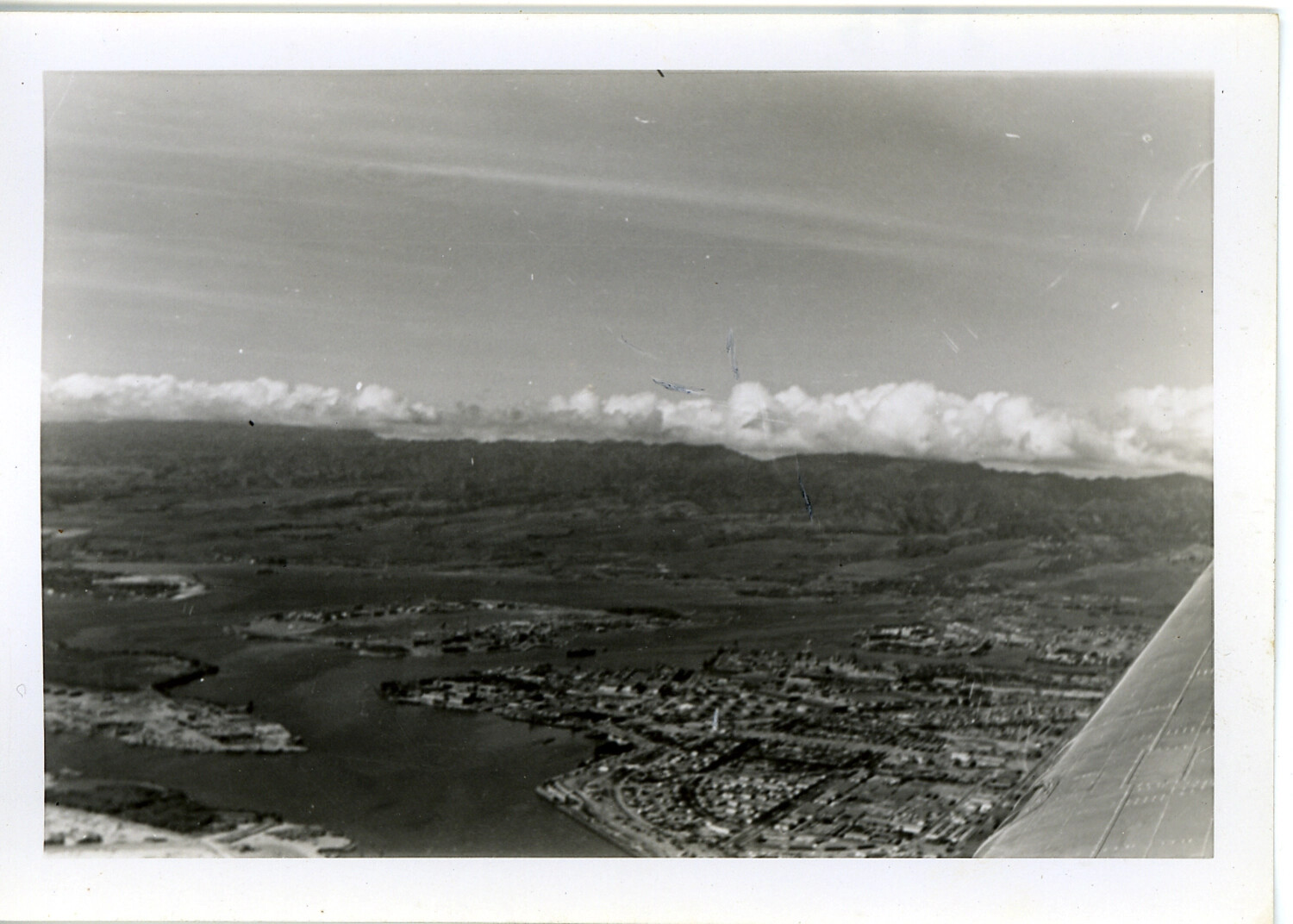 Aerial View of Hawaiian Harbor and Coastal Town from Aircraft Window, WWII Era