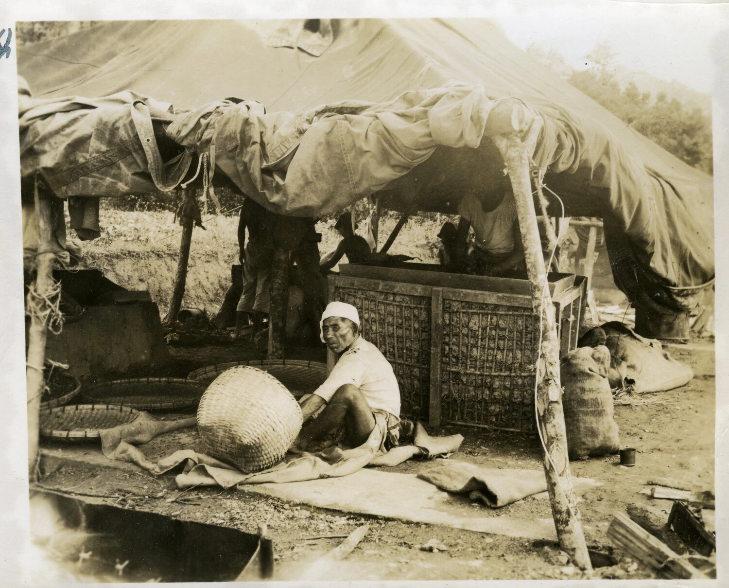 Okinawan Man Working with Woven Baskets Under a Canvas Shelter, Okinawa, WWII Era