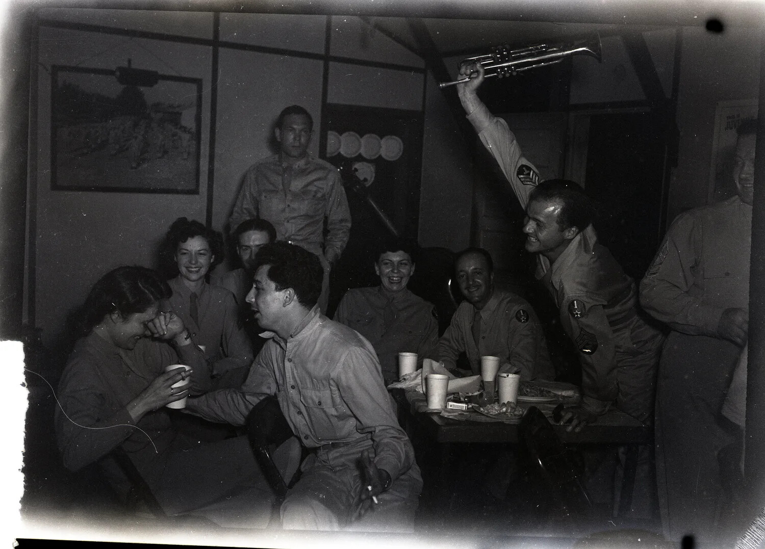 Servicemen and Guests Celebrating at Base Social Gathering with Trumpet