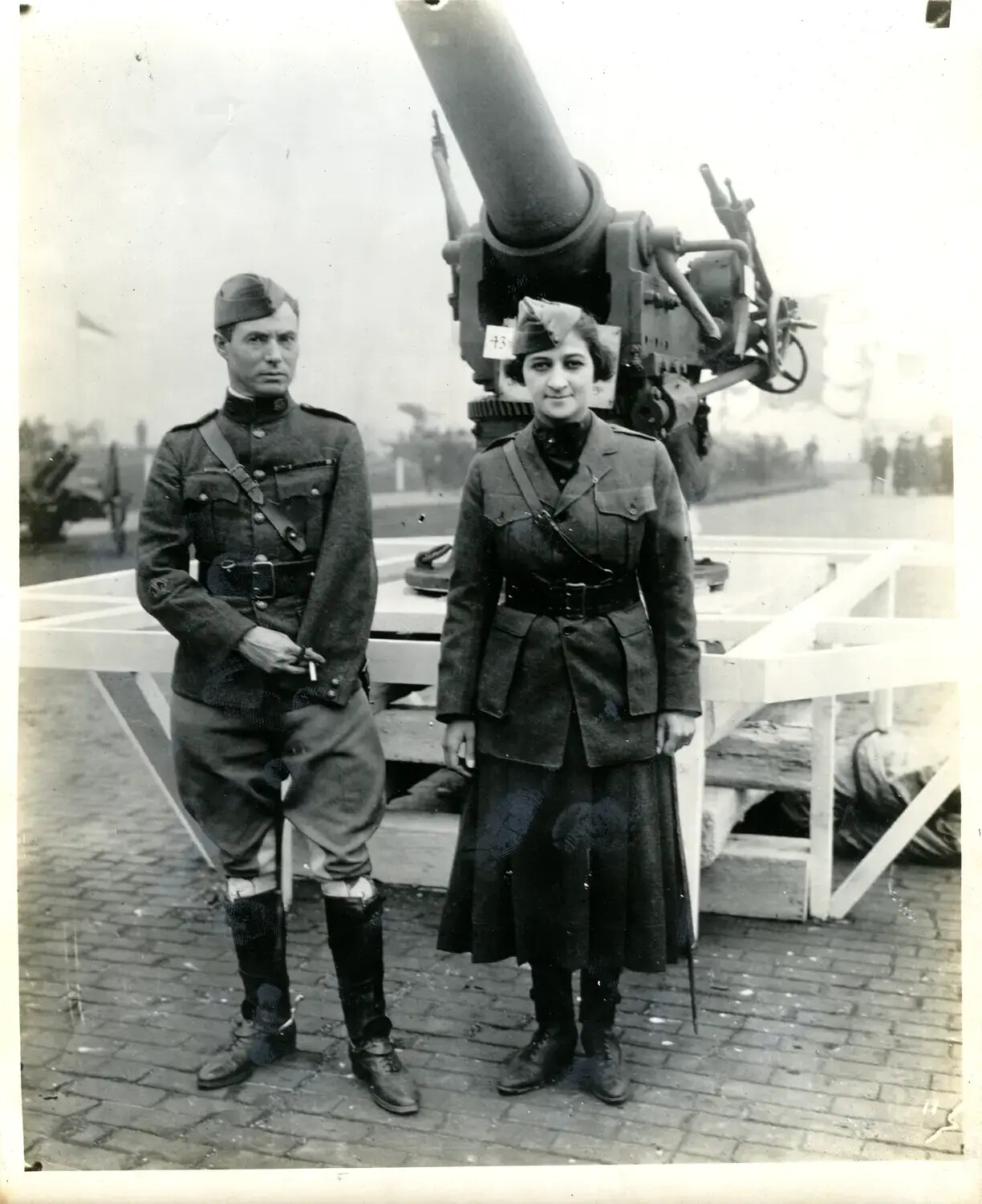 Uniformed Man and Woman Posing Before Trophy Field Gun, WWI War Exposition Grounds, [Cincinnati, Ohio], 1918
