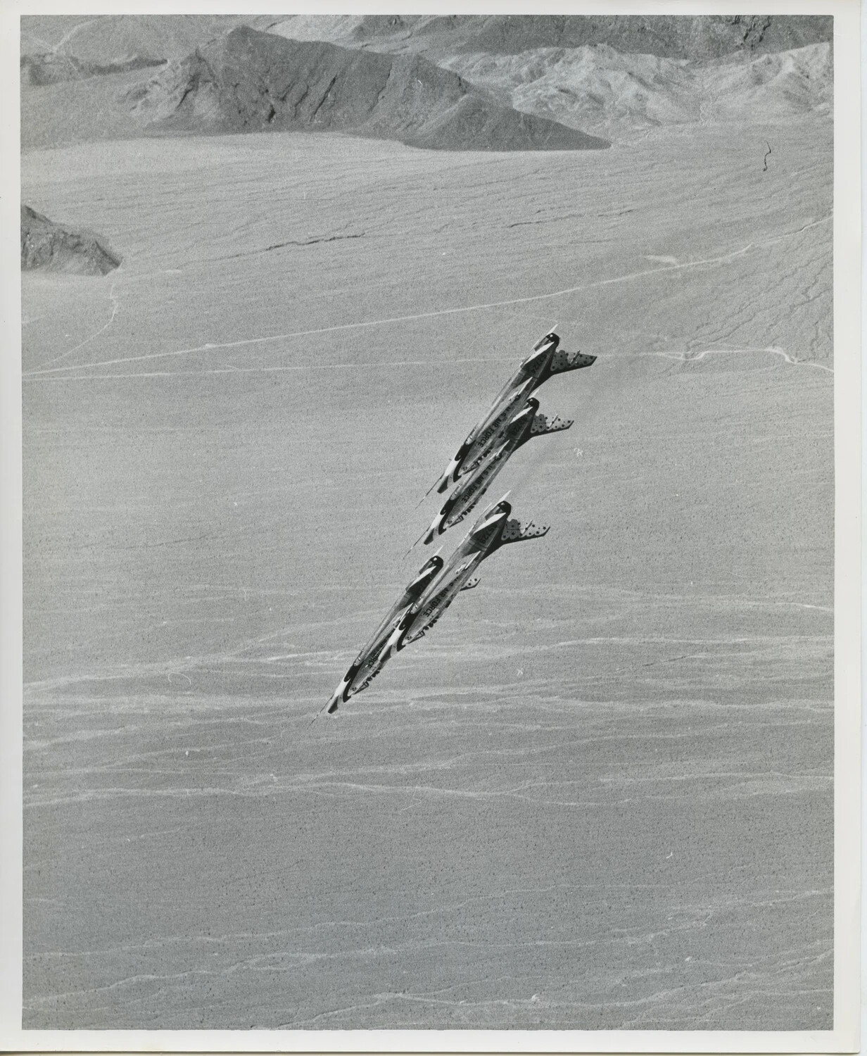 Thunderbirds F-100 Super Sabres Banking in Formation Over Desert Terrain
