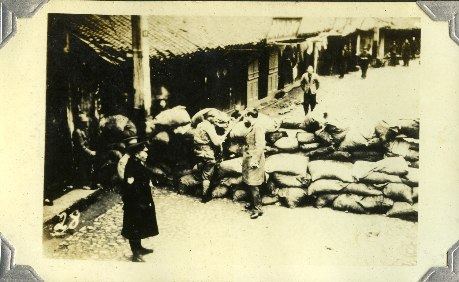 Sandbag Barricade with Armed Guard on Cobblestone Street, Possibly Manila or Another Asian City, Early 20th Century