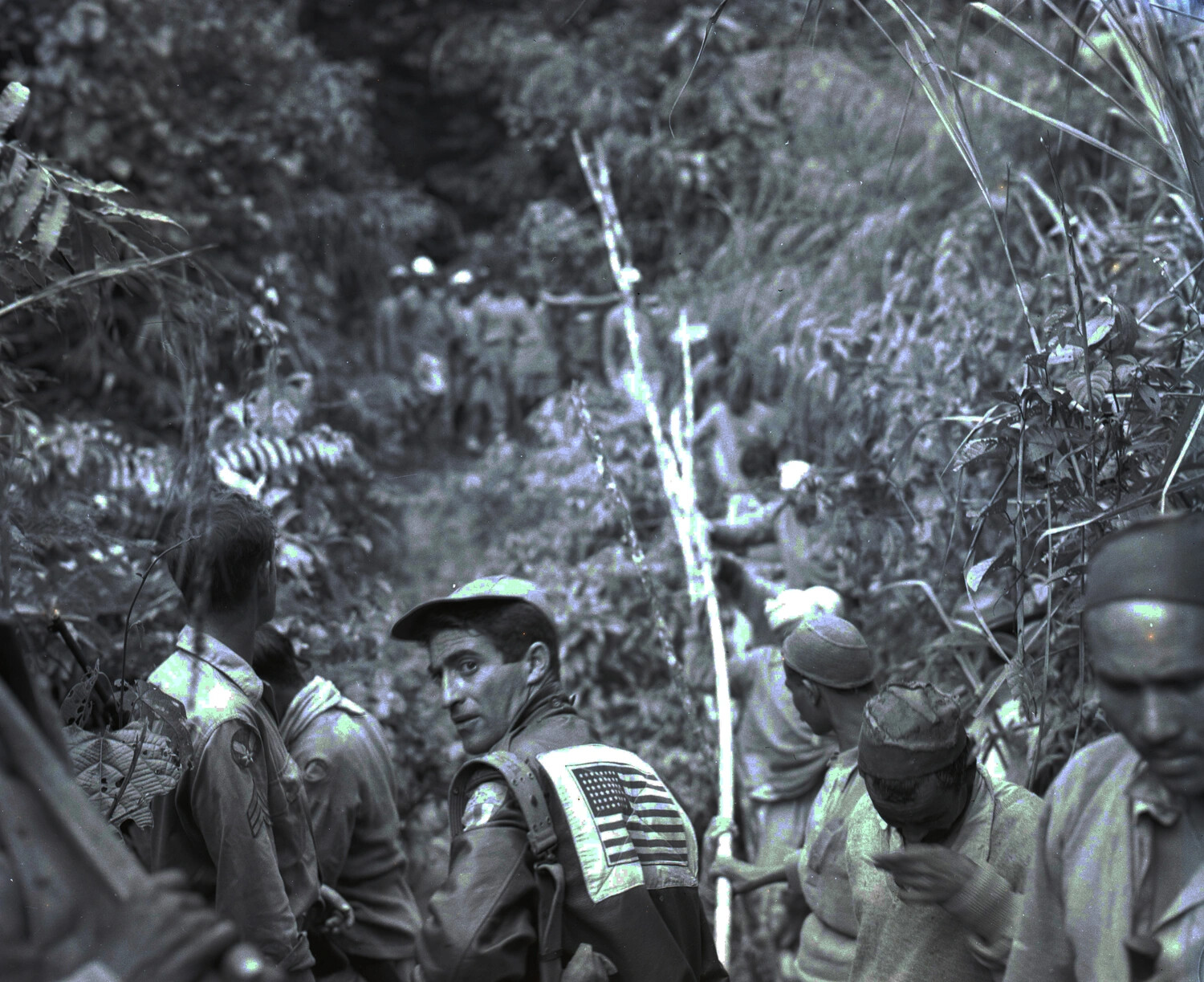 American Serviceman with American-Flag "Blood Chit" Jacket Panel Among Chinese Porters on Jungle Trail, CBI Theater, WWII