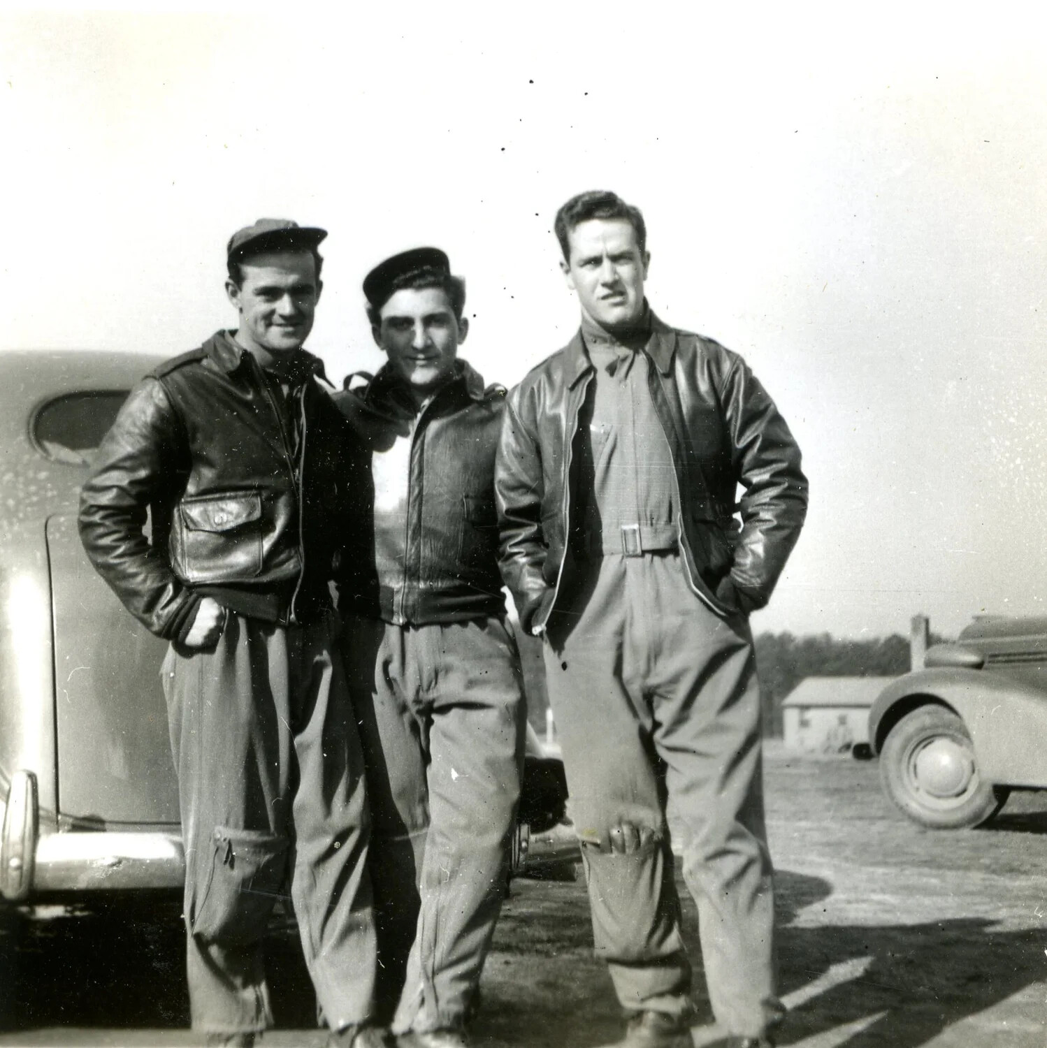 Three Airmen in Flight Jackets and Coveralls Posing Beside an Automobile