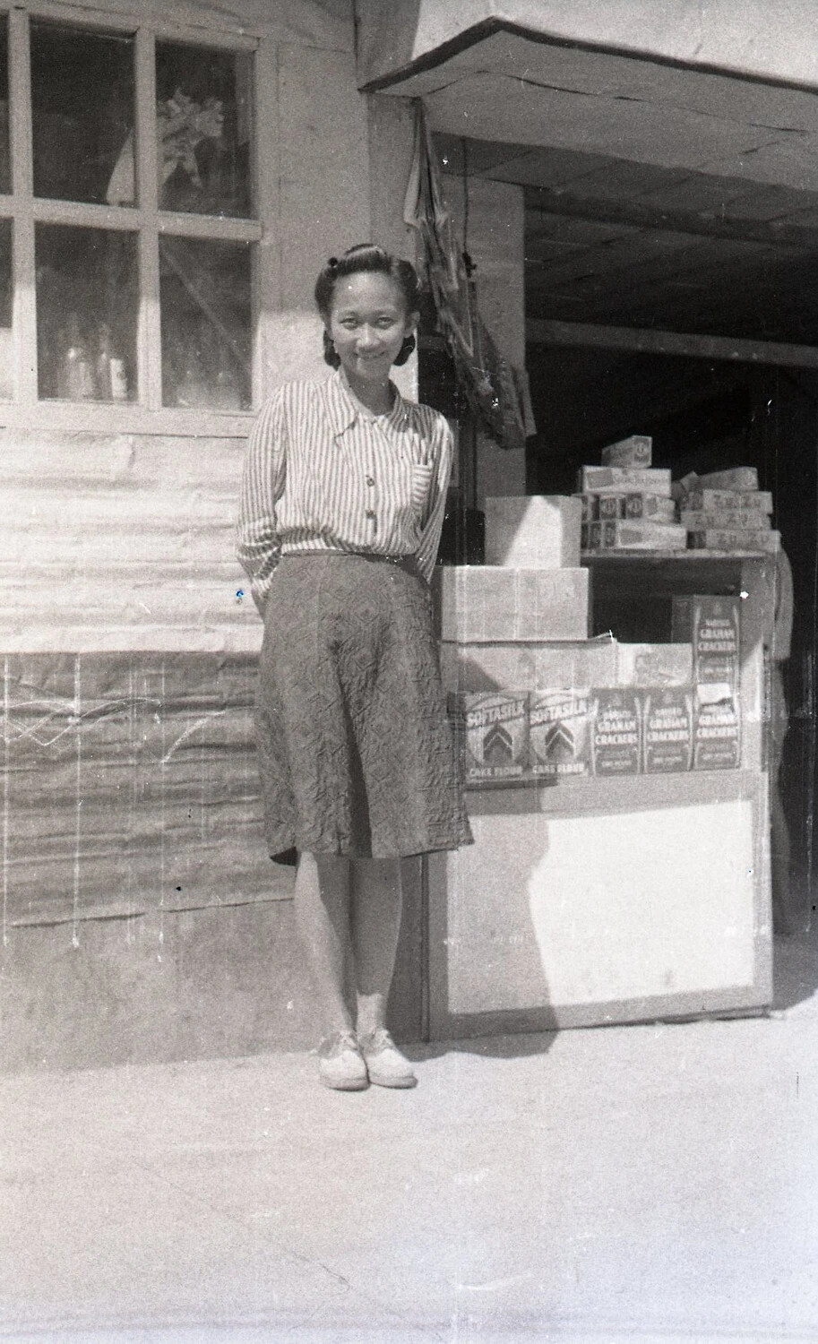Filipino Woman Beside Store Stocked with American Goods, Luzon, Philippines, World War II