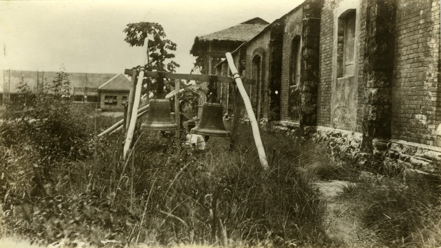 Two Bronze Bells on Wooden Frame Beside Damaged Colonial Building, Philippines, Early 1900s