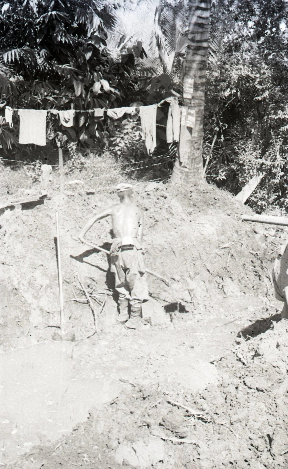 Serviceman Digging Near Laundry Line and Barbed Wire Fence, Luzon, Philippines, WWII