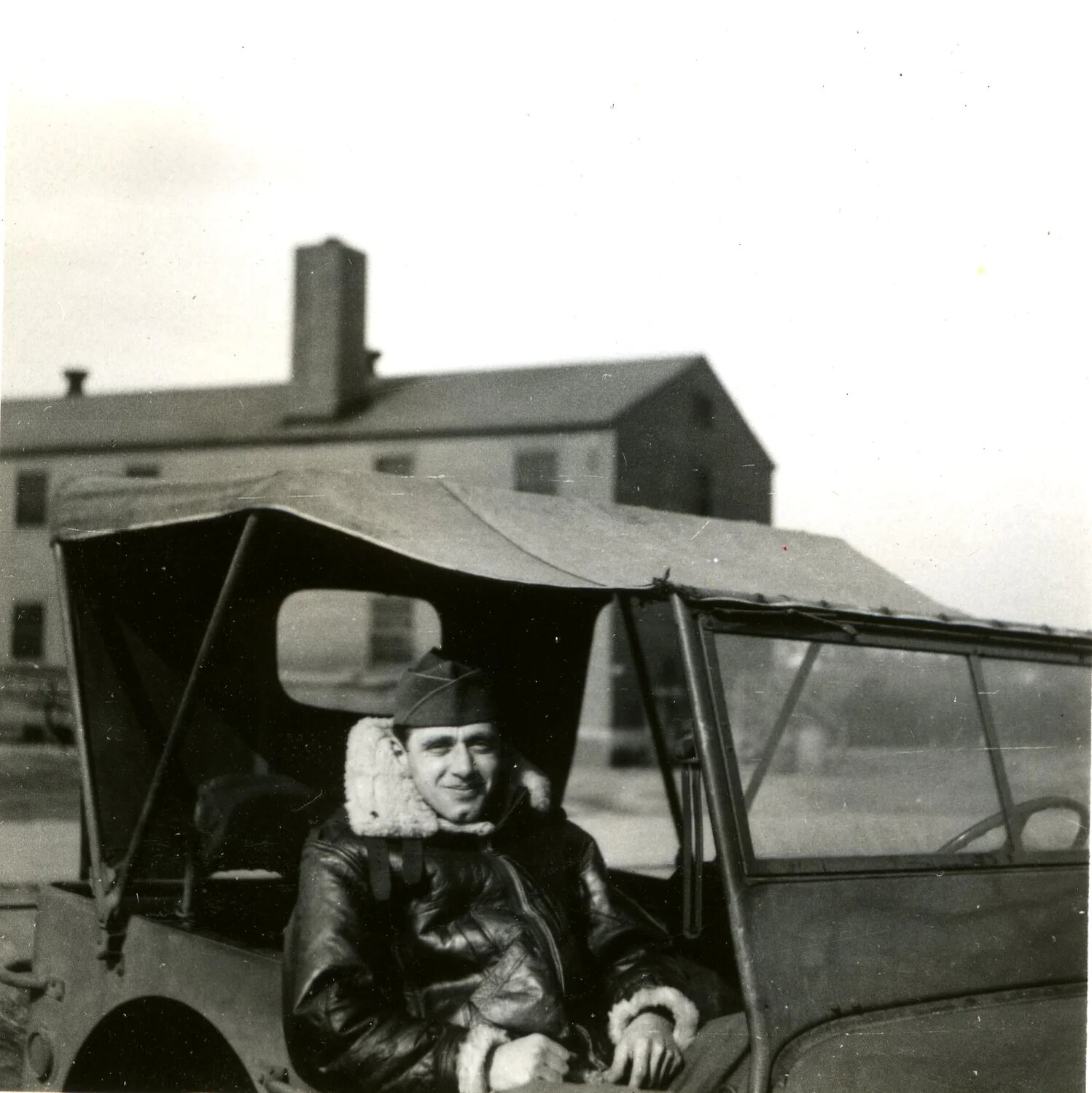 Airman in Fleece-Lined Flight Jacket Seated in Canvas-Top Military Vehicle at Training Base