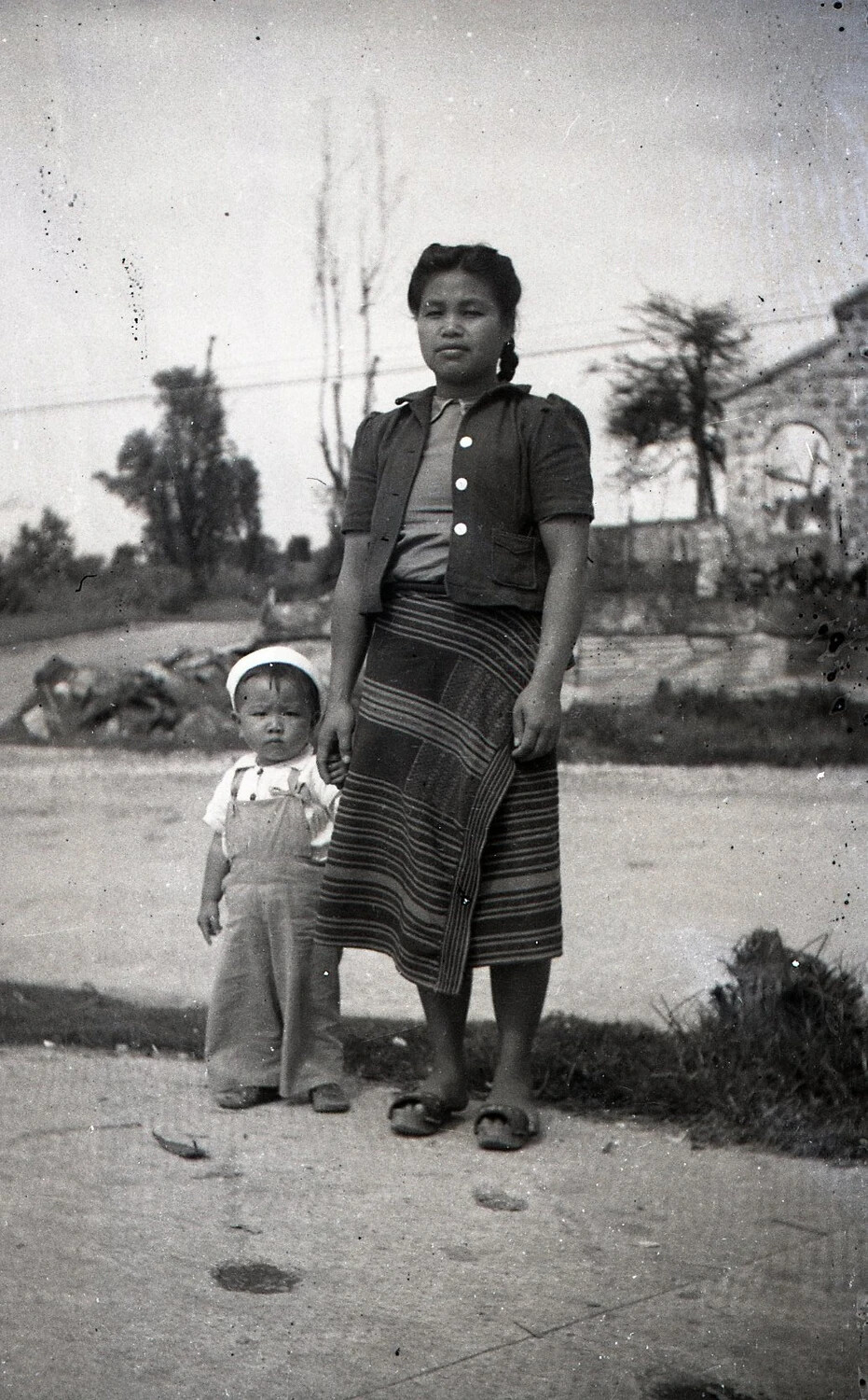 Filipina Woman and Child Beside War-Damaged Structure, Luzon, Philippines, World War II Era