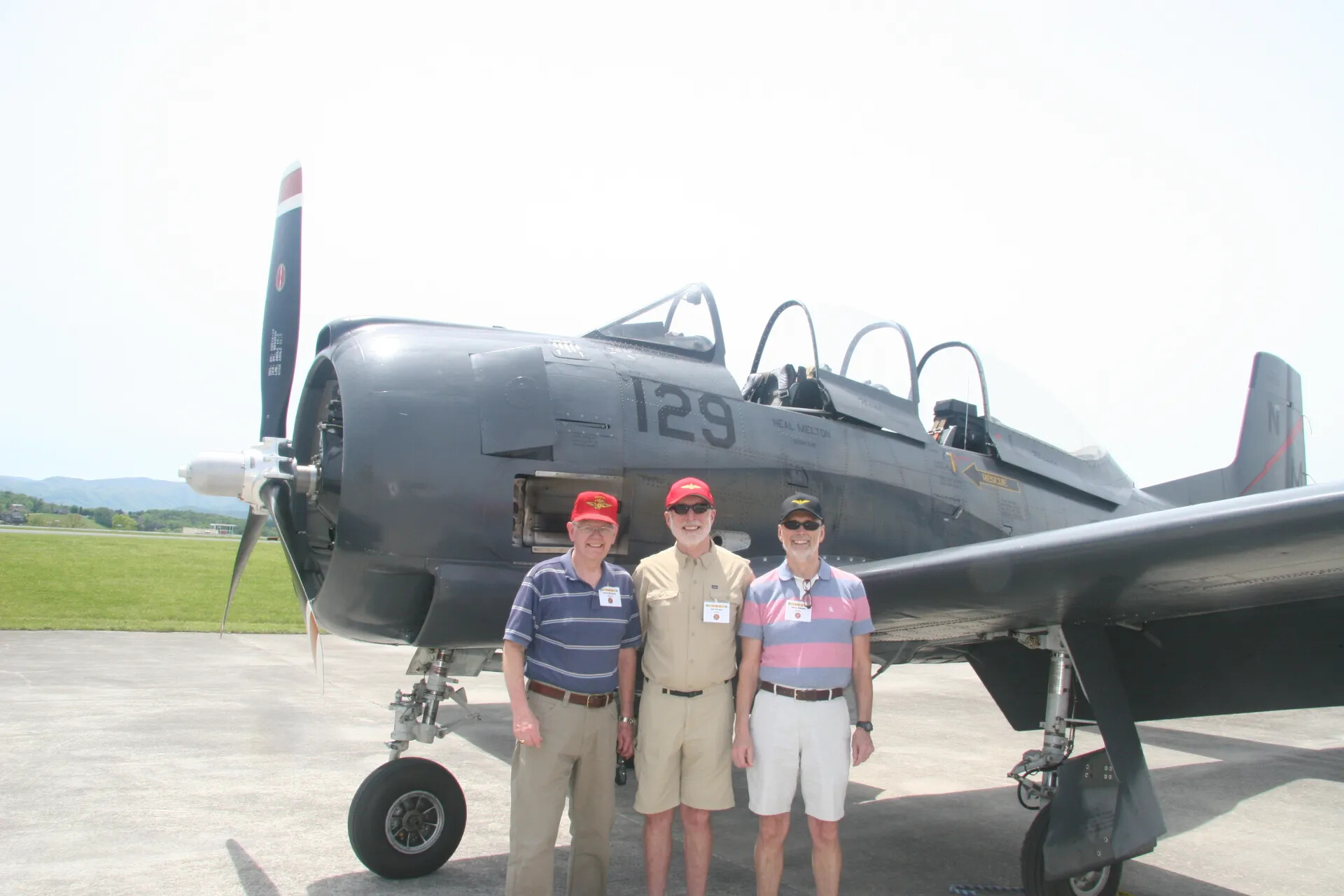 Three Veterans Pose with North American T-28 Trojan No. 129 'Neal Melton' at Reunion Fly-In