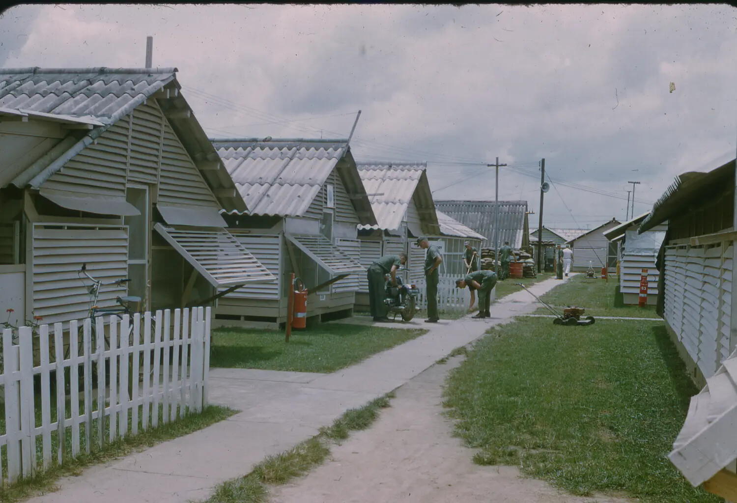 Airmen's Billeting Area ('Hootches') with Motorcycle and Lawn Maintenance, U.S. Air Base, Vietnam, 1965