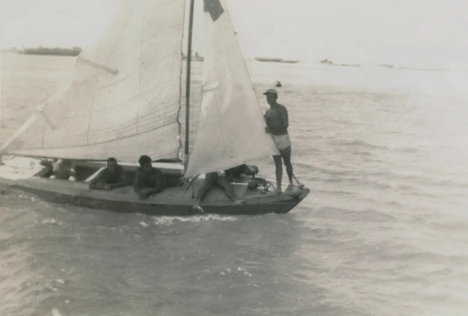 Local Sailboat Alongside Allied Shipping in a Pacific Harbor, WWII Era