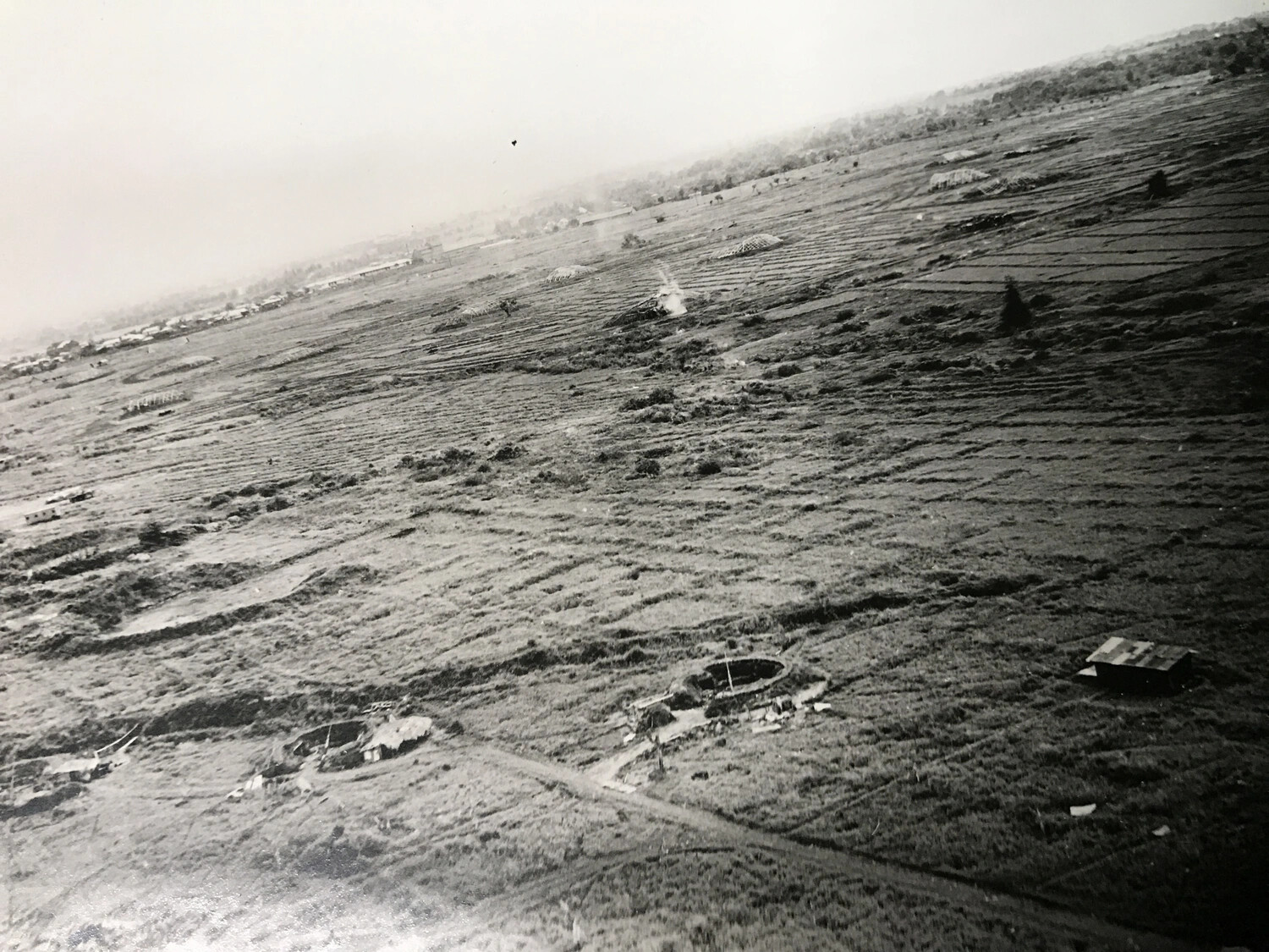 Aerial View of Cultivated Fields with Circular Earthworks and Smoke Plume