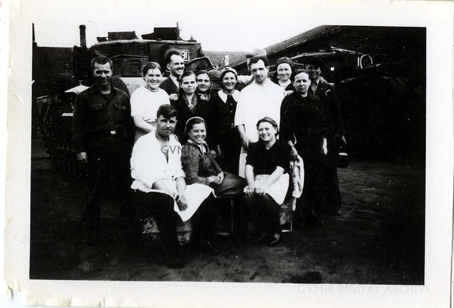 American Soldier with Factory Workers Beside a Captured Armored Vehicle, Germany/Austria, 1945