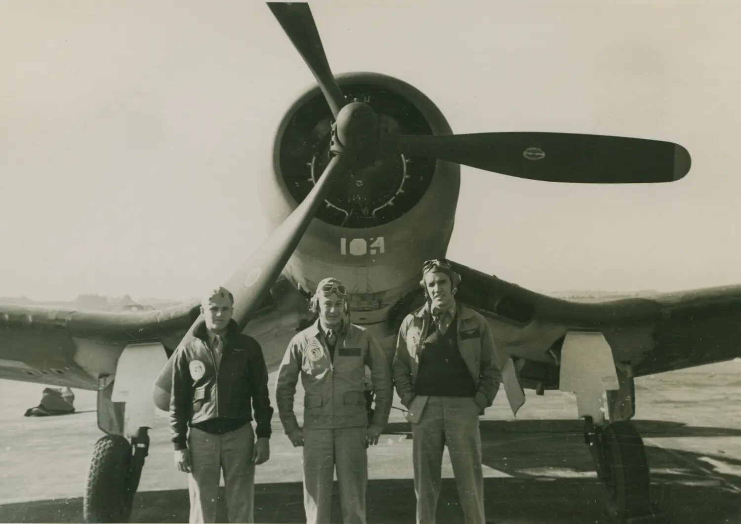 Three Aviators Posing Beneath the Nose of a WWII Single-Engine Radial Fighter Aircraft