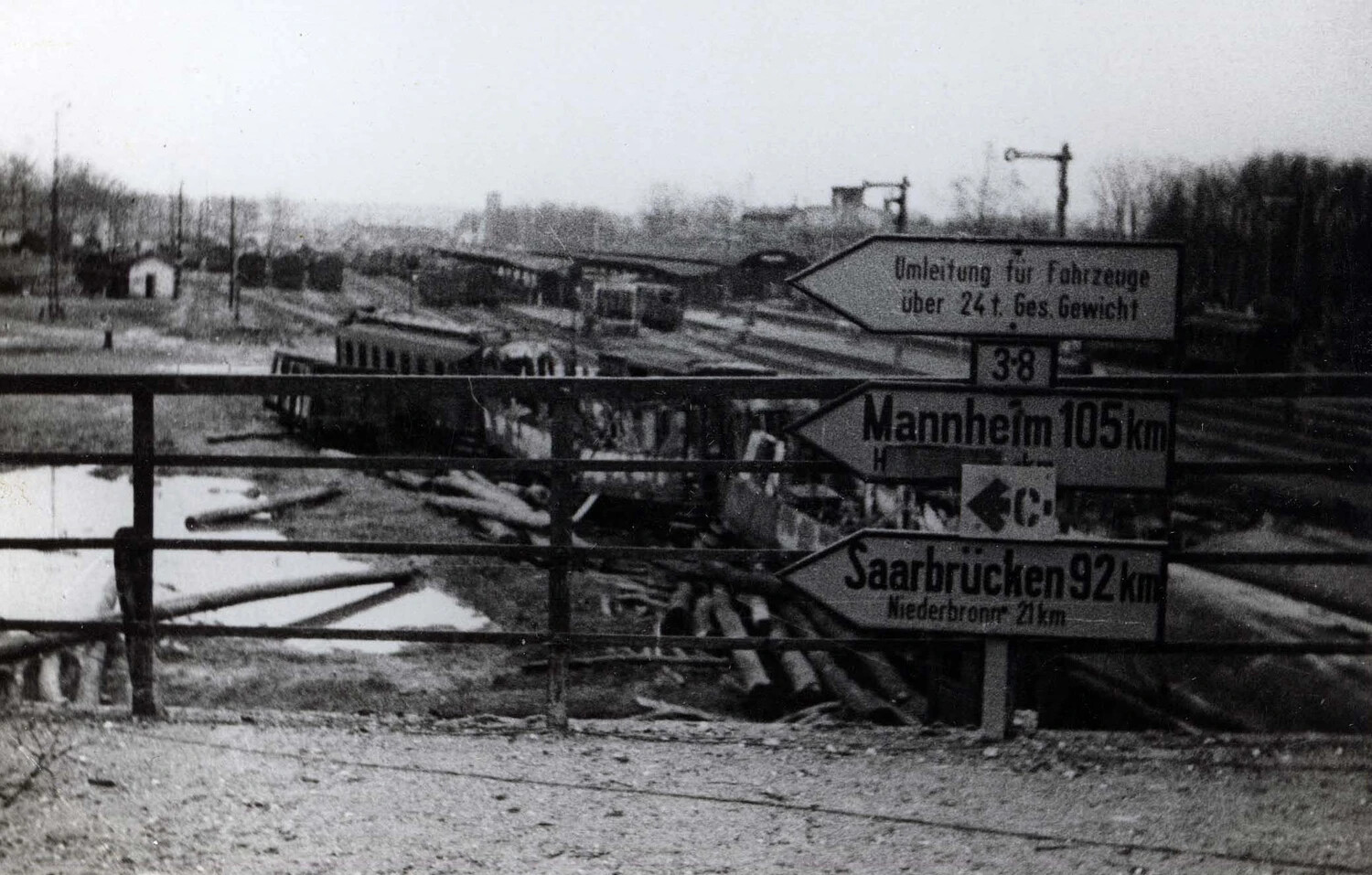 German Road Signs Directing to Mannheim, Saarbrücken, and Niederbronn Above a Wrecked Rail Yard, WWII