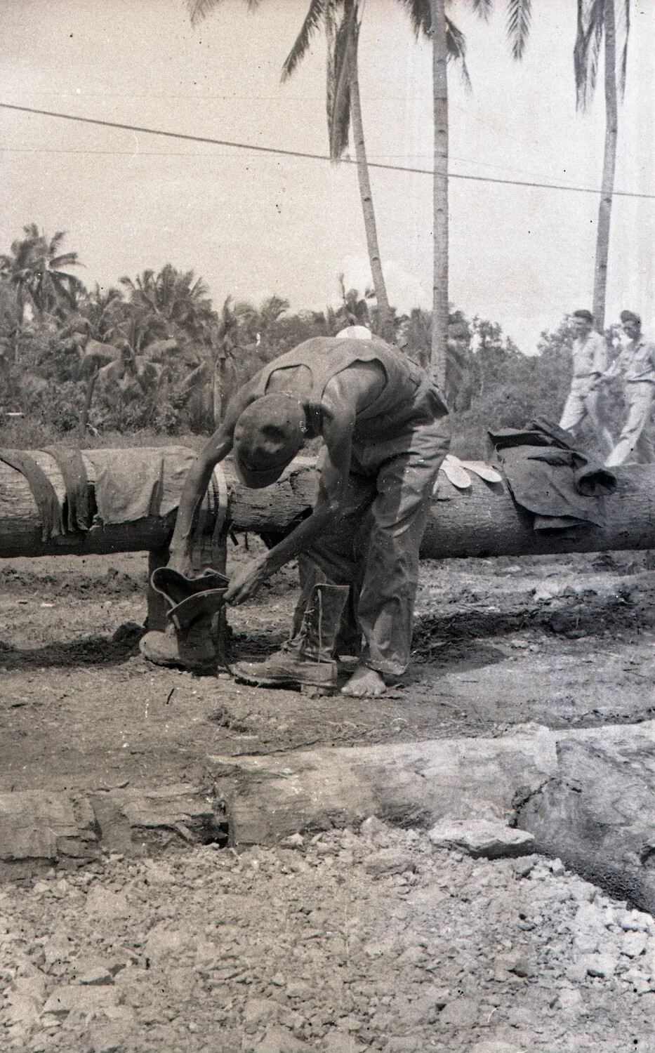 Serviceman Retrieving Boots After Concrete Work at Engineering Camp, Luzon, Philippines, WWII