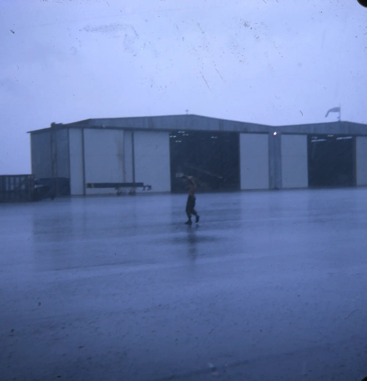 Serviceman Running Through Monsoon Rain on Airfield Apron, Vietnam War