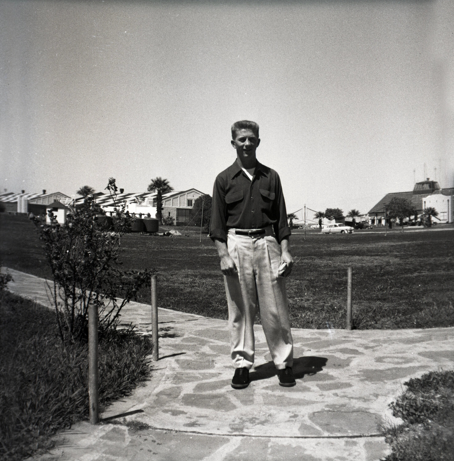 Young Man in Civilian Attire on Base Walkway, USAF Installation, 1950s