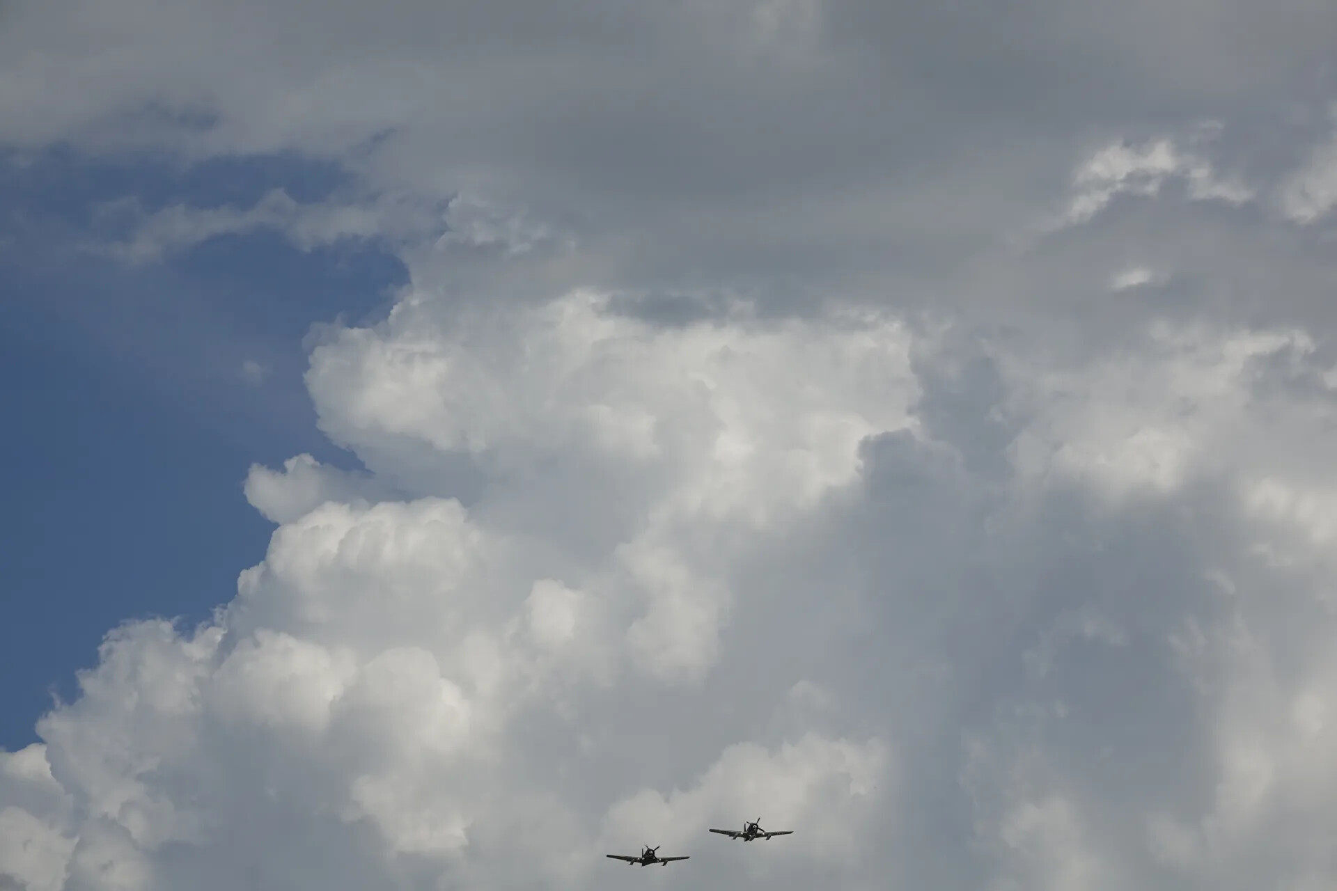 Two Vintage Radial-Engine Aircraft in Formation Flight Against Cumulus Clouds