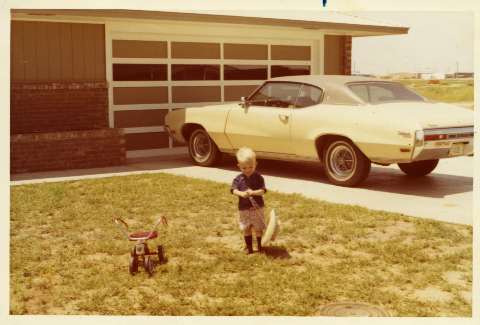 Family Snapshot: Child on Front Lawn with Tricycle and Automobile, Doug Carmichael Collection, Early 1970s