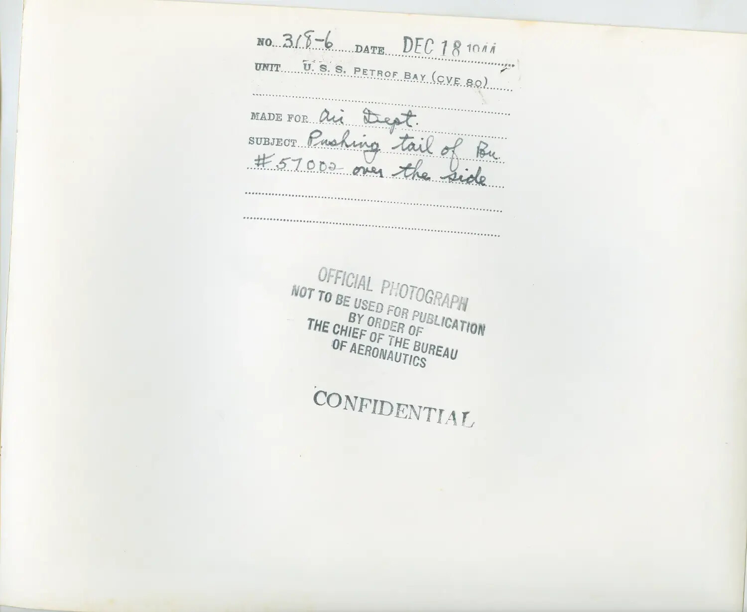 Official U.S. Navy Photograph Caption Card - USS Petrof Bay (CVE-80), 'Pushing Tail of Bu. #57002 Over the Side,' December 18, 1944
