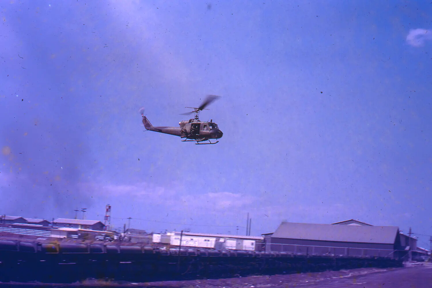 UH-1 Huey Helicopter in Low Flight Over Rail Yard, Vietnam, 1968 Tet Offensive Era