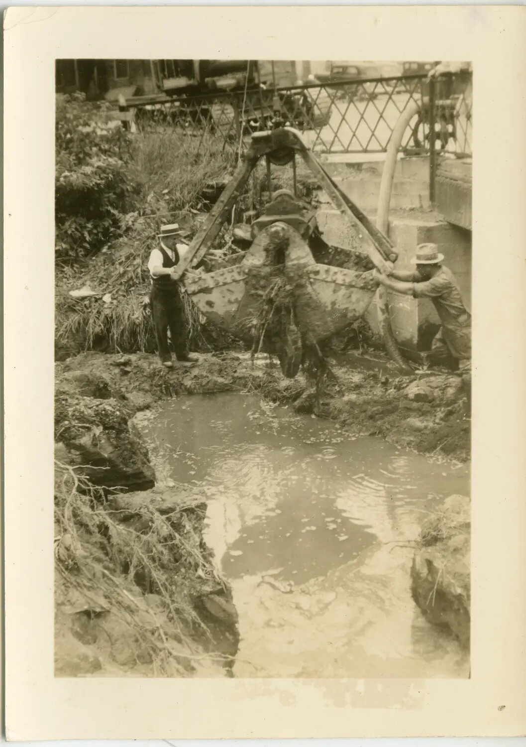 Men Operating a Clamshell Dredge Bucket in a Drainage Channel (Non-Aviation Photograph, Margaroli Collection)