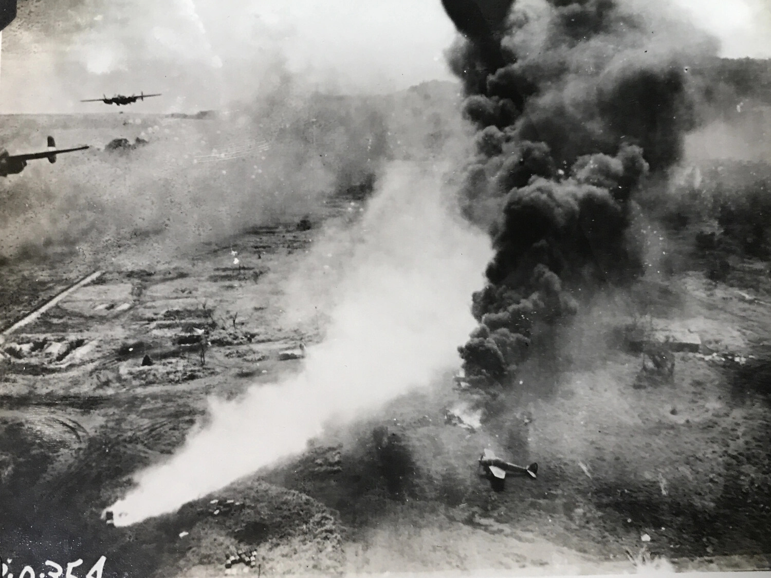 B-25 Mitchells Over Cratered Target with Grounded Aircraft and Smoke Column, Reference Partially Legible