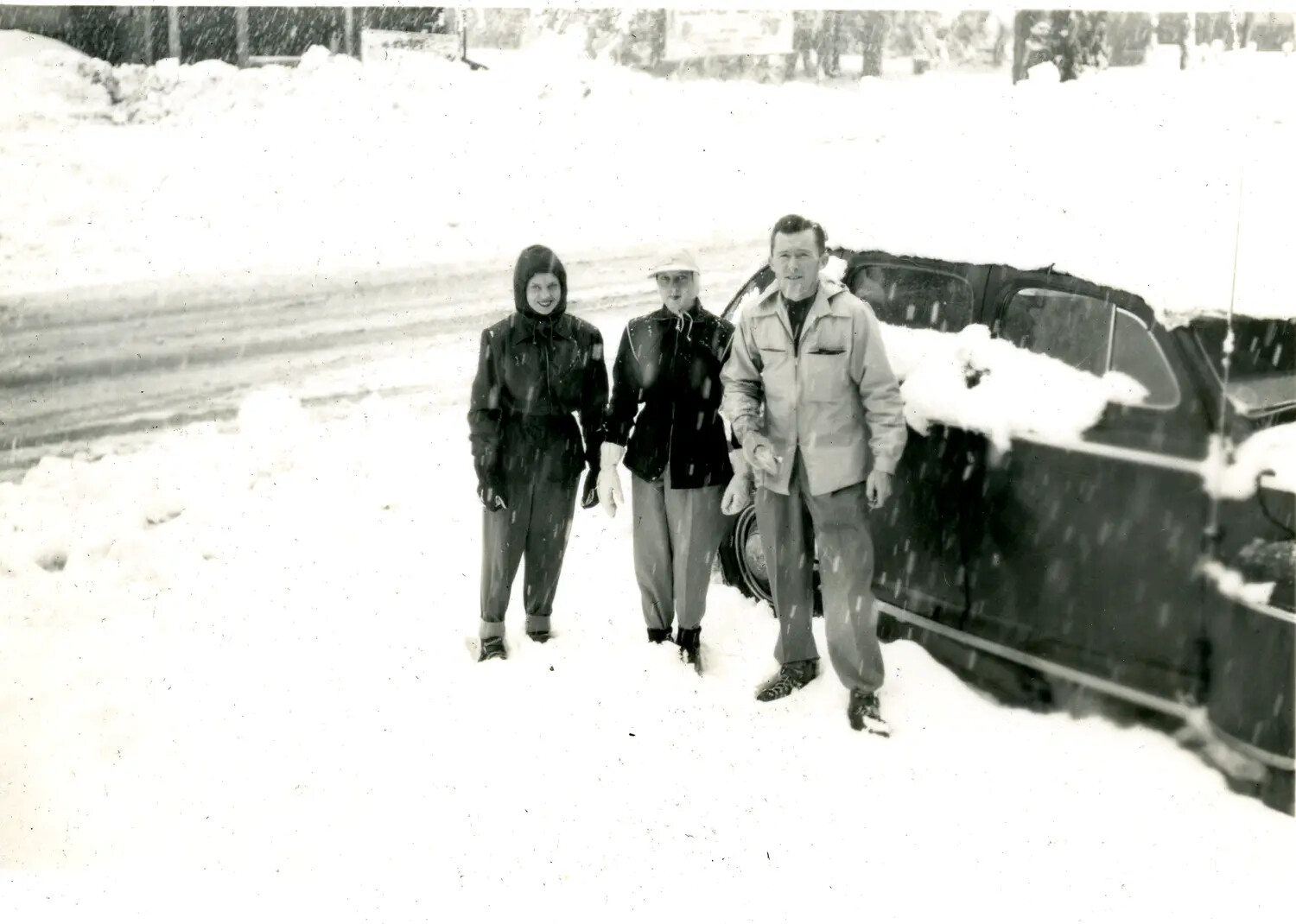 Snapshot of Three People in a Snowstorm Beside a Parked Car
