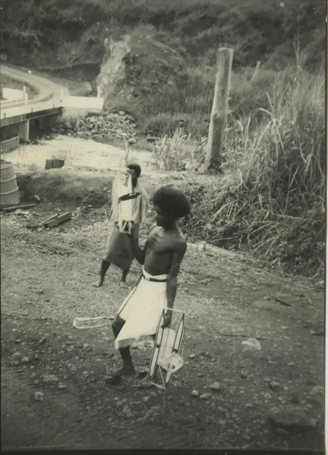 Local Melanesian Men Carrying Woven Frames Near a Military Bridge