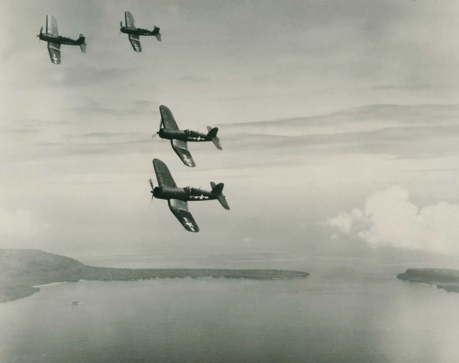 Four F4U Corsair Fighters in Formation Over Pacific Atoll, WWII