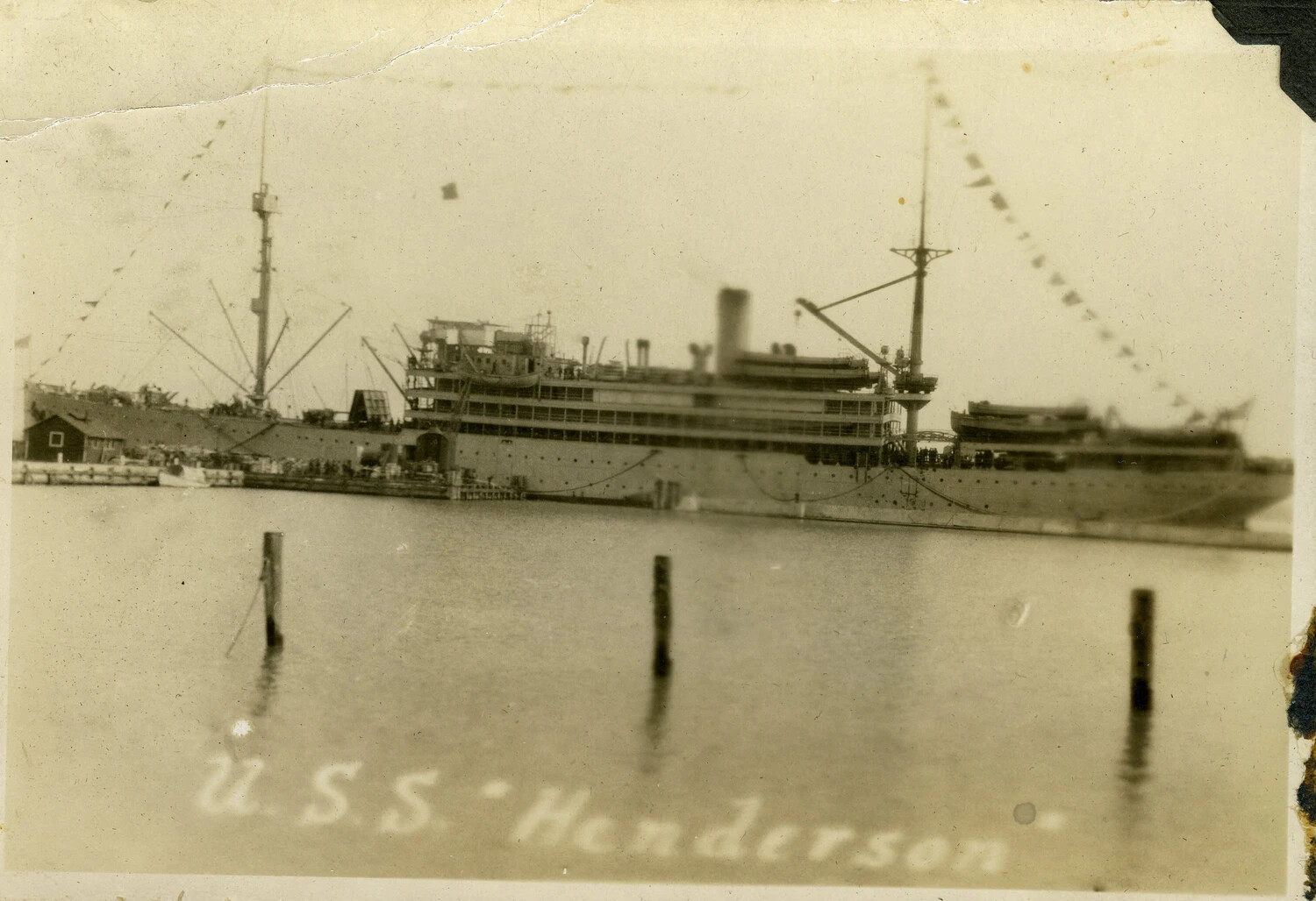 USS Henderson (AP-1) Dressed with Signal Flags, Moored at Pier