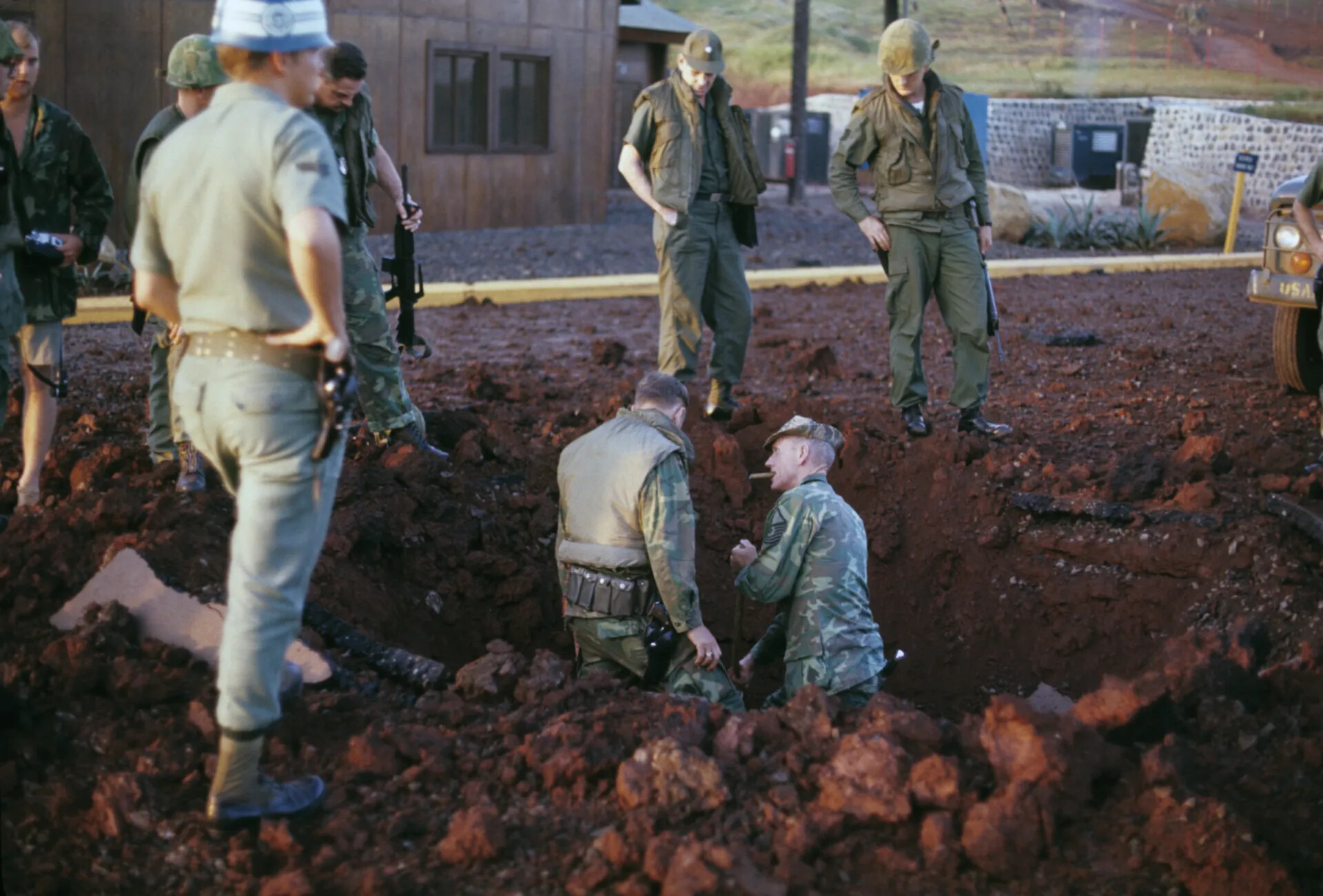 Security Personnel Inspecting Bomb/Rocket Crater, U.S. Air Base, Southeast Asia, circa 1970