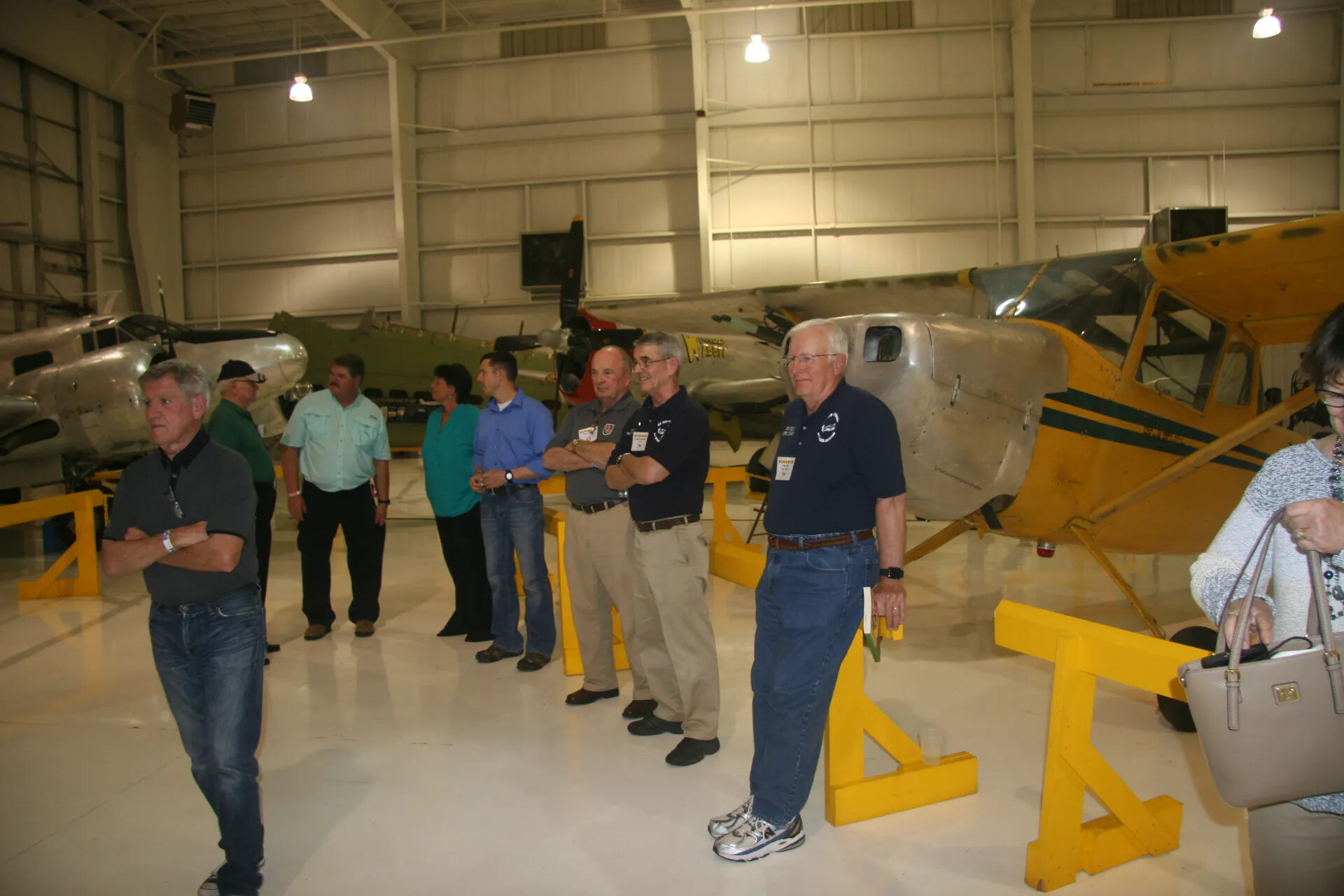 Reunion Group Standing in Formation Before Vintage Aircraft, Museum Hangar