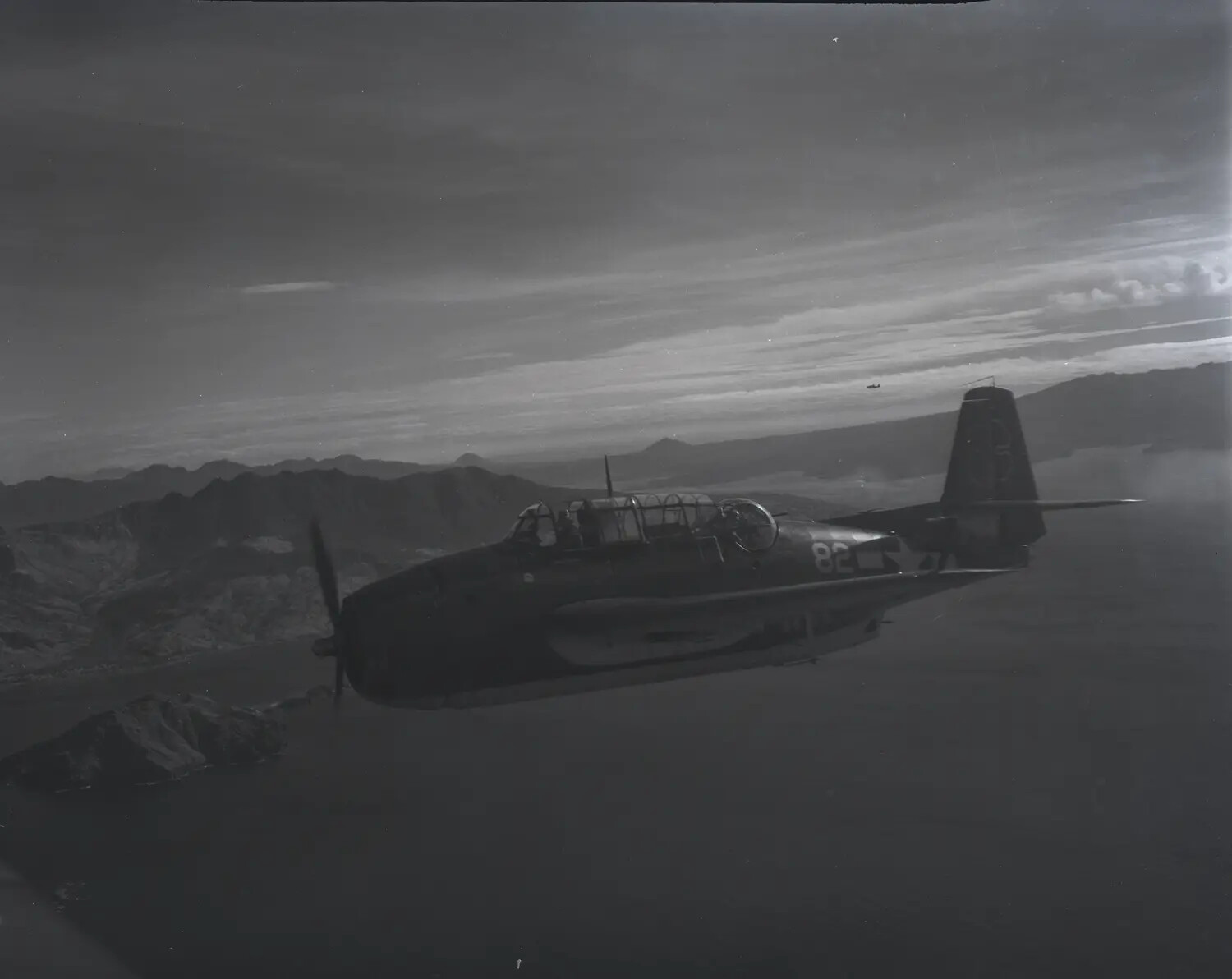 TBM/TBF Avenger '82' in Flight Over Mountainous Coastline, Pacific Theater, World War II